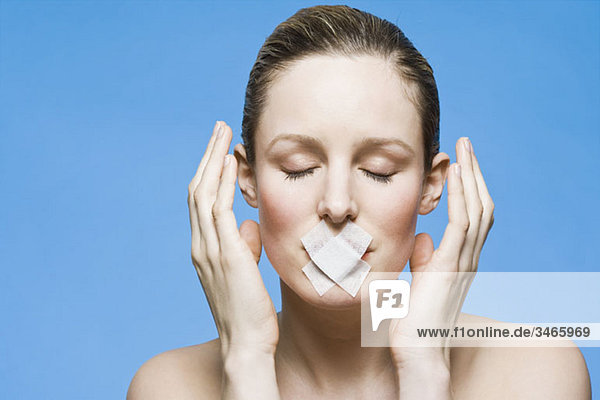 A woman with tape covering her mouth  gesturing in frustration