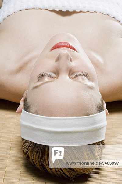 Eine Frau liegt auf einer Tatami-Matte  die Augen geschlossen.