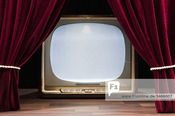 Ein altmodisches Fernsehen hinter roten Theatervorhängen