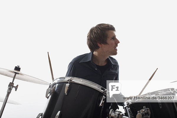 Ein Mann am Schlagzeug  Studioaufnahme  weißer Hintergrund  hintergrundbeleuchtet