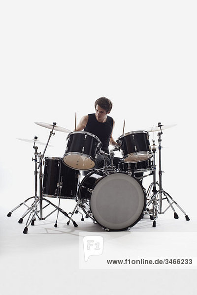 Ein Mann am Schlagzeug spielt  Studioaufnahme  weißer Hintergrund  hinterleuchtet