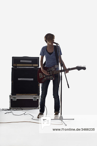 Eine Frau singt und spielt E-Gitarre  Studioaufnahme  weißer Hintergrund  hintergrundbeleuchtet