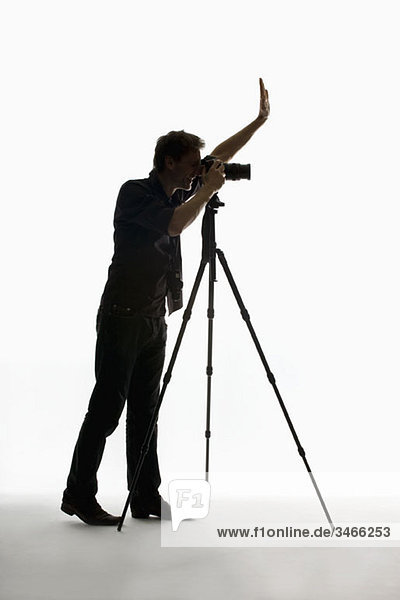 Ein Fotograf  der mit einer Kamera auf einem Stativ arbeitet.