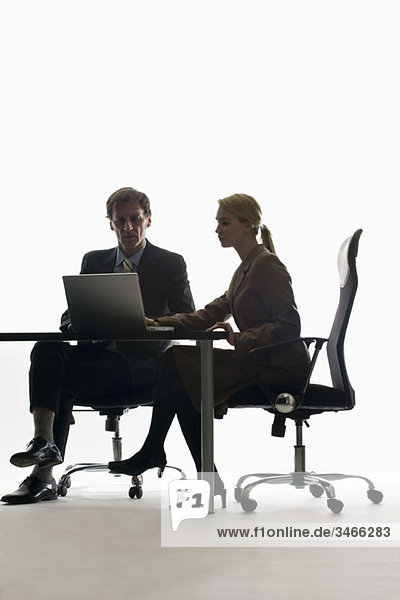 Eine Geschäftsfrau und ein Geschäftsmann  die mit einem Laptop zusammenarbeiten.