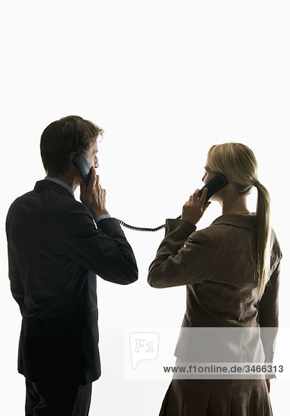 Two business people using phone receivers connected with the same cord