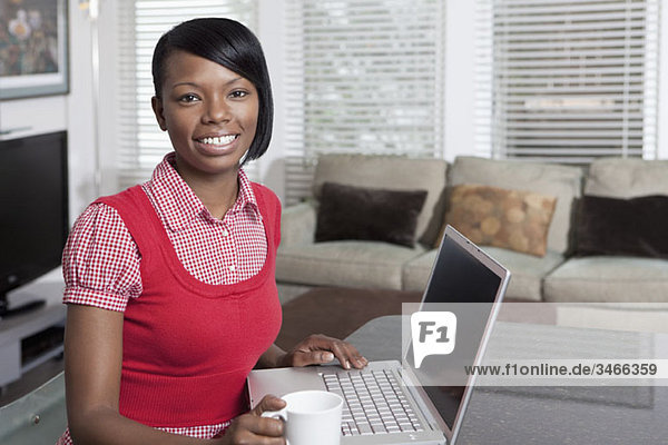 Portrait of a woman sitting at a table with a laptop