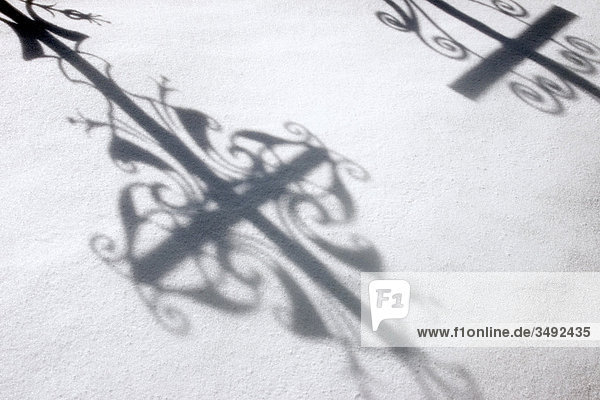 Schatten von Grabkreuzen im Schnee Friedhof in Leutasch Tirol Österreich