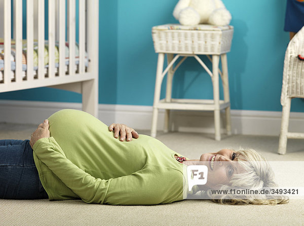 Schwangere ältere Frau auf dem Boden liegend