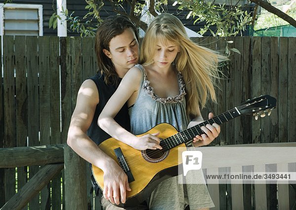 Mädchen spielt Gitarre mit jungem Mann