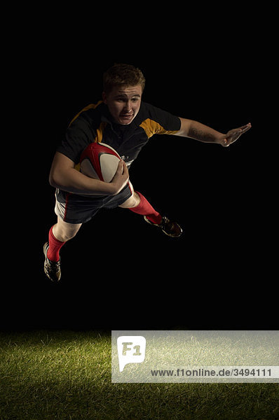 Rugbyspieler in der Luft mit Ball