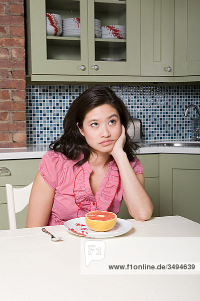 Young woman eating grapefruit