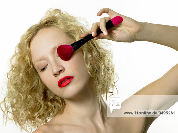 Junge Frau beim Auftragen von Lidschatten mit Make-up-Pinsel