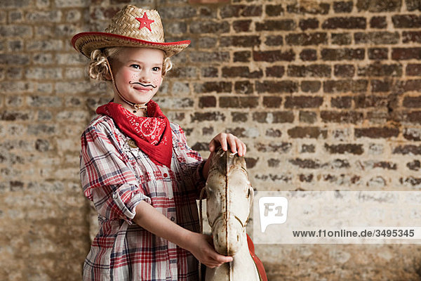 Young girl dressed as cowgirl with rocking horse