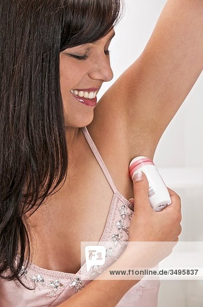 young woman using deodorant in her bathroom