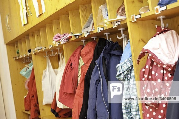 Kleidung in der Garderobe eines Kindergartens hängend