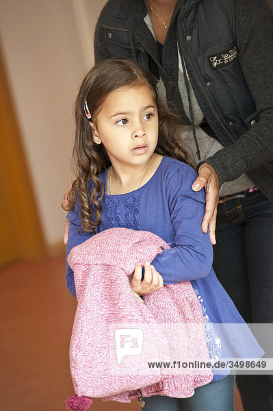 Kindergärtnerin steht hinter einem Mädchen