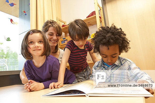 Kindergarten teacher and children looking at a book  low angle view