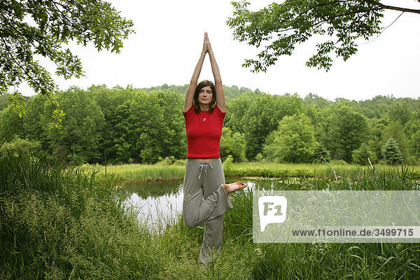 Frau praktiziert Yoga in der Natur  Frontalansicht