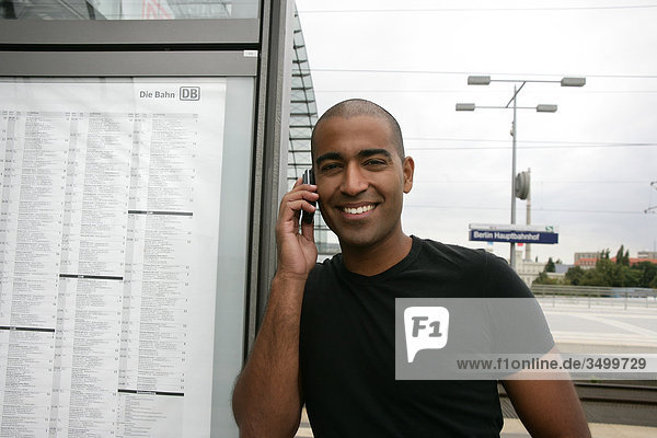 Mann telefoniert auf einem Bahnhof  Frontalansicht
