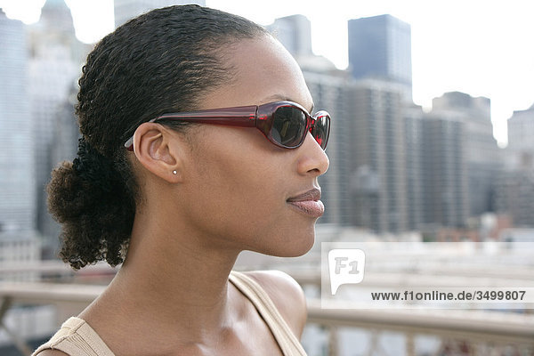 Junge Frau mit Sonnenbrille  Skyline im Hintergrund  Porträt