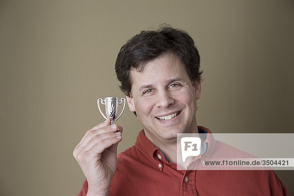 Mann Lächeln halten eine sehr kleine Trophy-Tasse