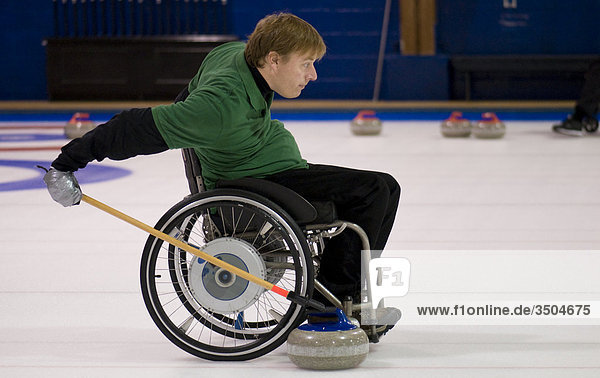 Mann im Rollstuhl vorbereiten  Curling Stein mit Extender-Stick  Curling Club  Toronto  Ontario drücken