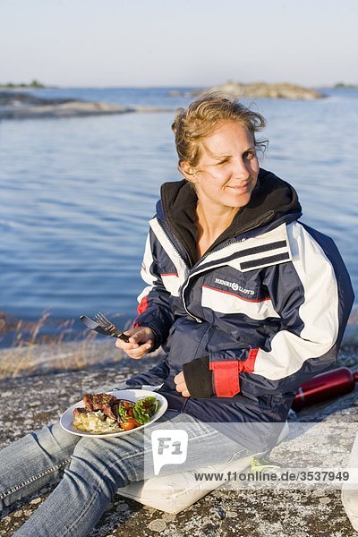Woman having dinner on a rock  Sweden