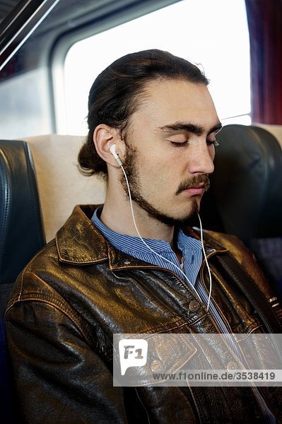 Man sitting in train with eyes closed and listening music