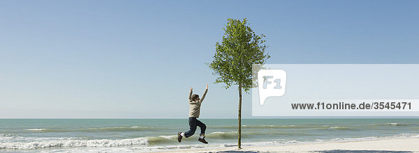 Junge beim Springen in der Luft am Strand