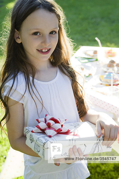 Mädchen bei Geburtstagsfeier mit verpacktem Geschenk