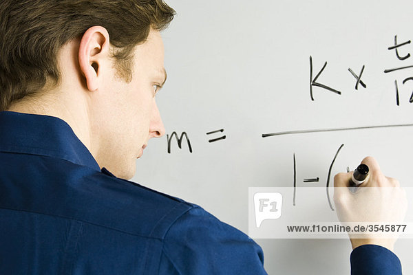 Mann schreibt Gleichung auf Whiteboard