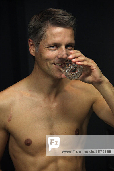 Mann trinkt aus einem Wasserglas