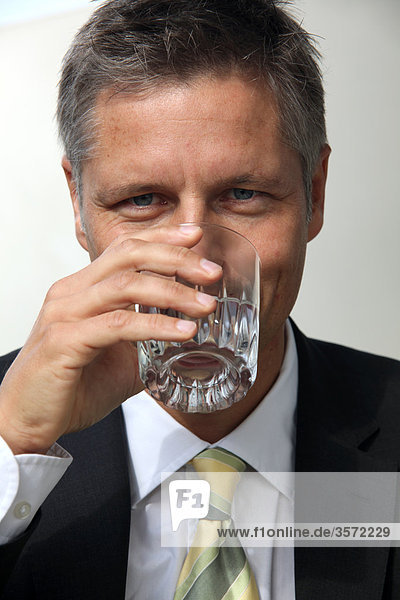 Geschäftsmann trinkt aus einem Wasserglas  Portrait
