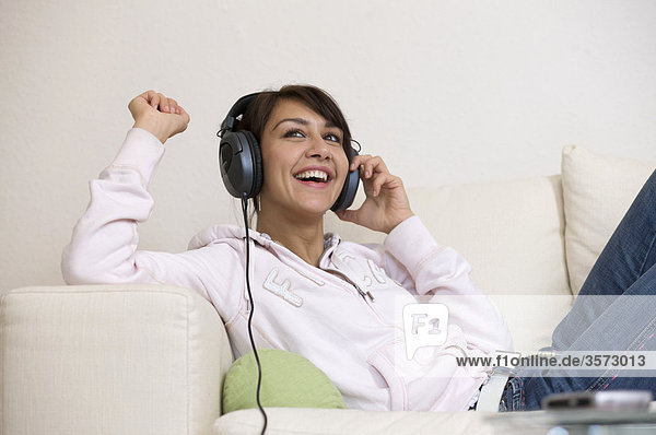 Happy woman in living room wearing headphones