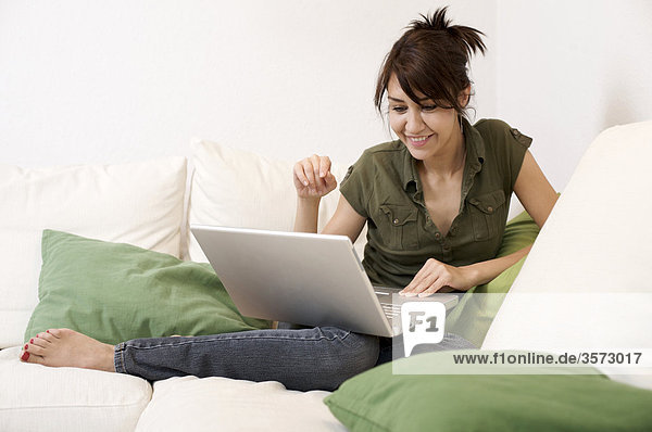 Lächelnde Frau im Wohnzimmer mit Laptop