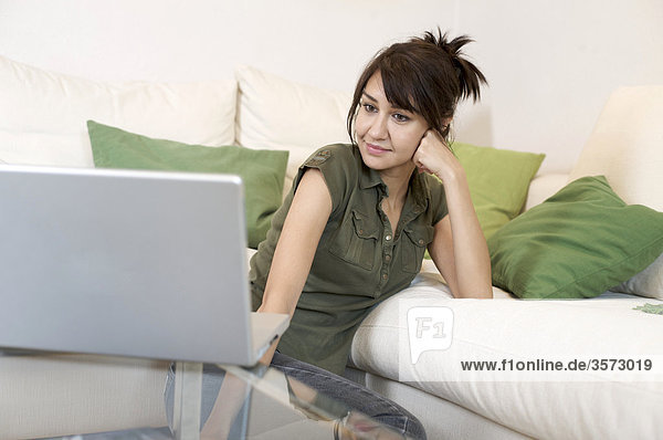 Content woman in living room looking at laptop