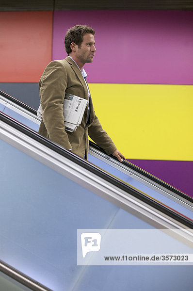 Man with newspaper on escalator