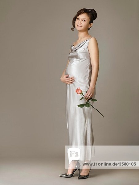 Beautiful pregnant young young woman with a red rose