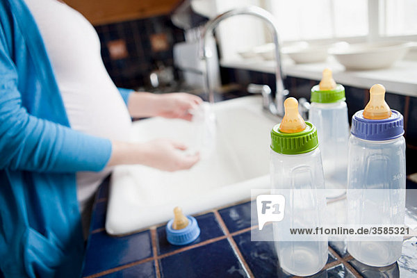 Schwangere Frau beim Waschen von Babyflaschen