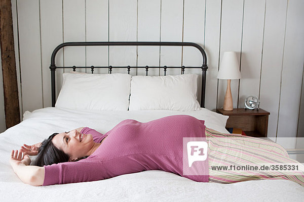 Schwangere Frau liegt auf dem Bett