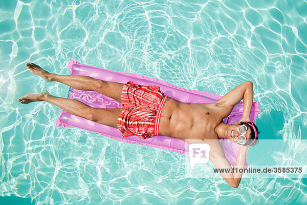 Mann auf einer aufblasbaren Matratze im Pool