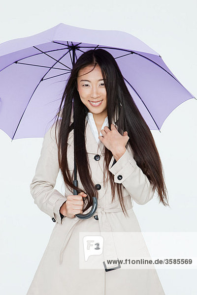 Frau im Regenmantel mit Regenschirm
