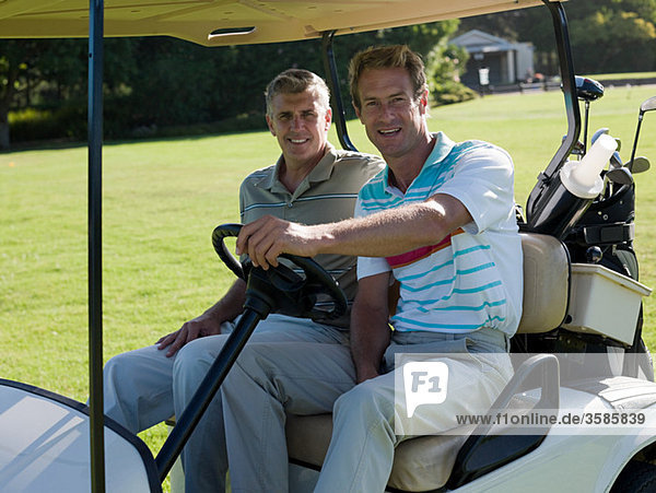 Two mature men in golf cart on golf course