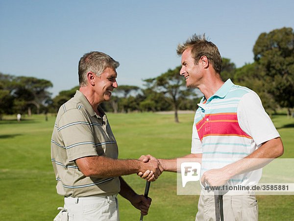 Zwei ältere Männer Händeschütteln auf Golfplatz