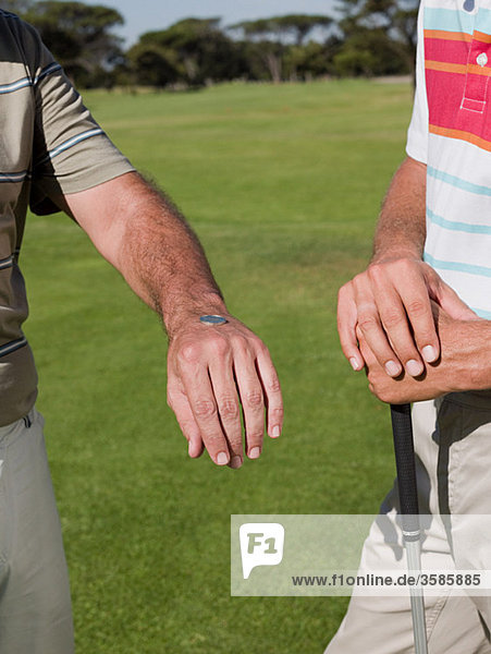 Zwei ältere Männer zusammen Golf zu spielen  werfen einer Münze