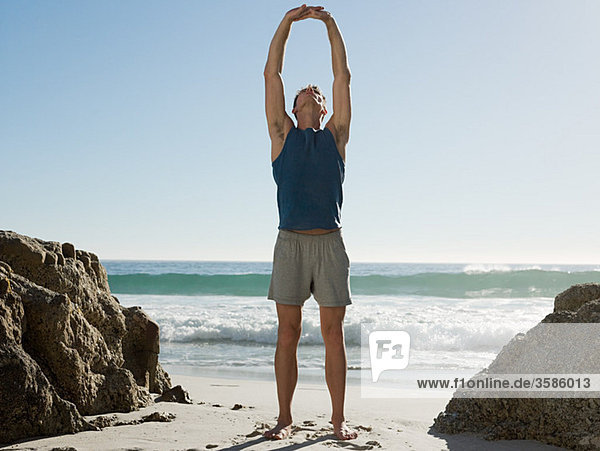 Young man doing yoga on beach