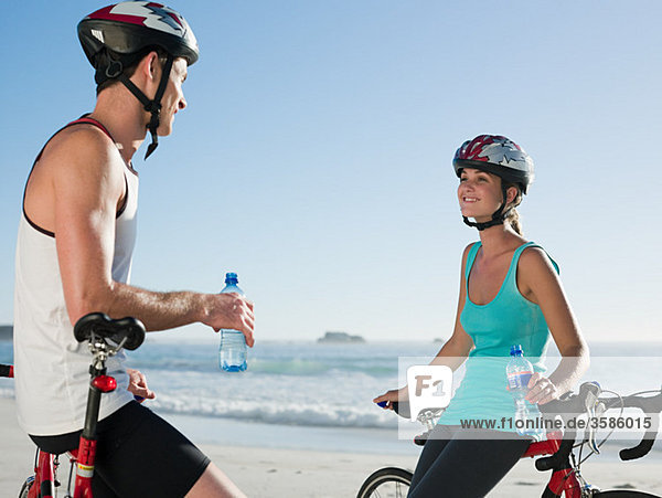 Young couple cycling at beach