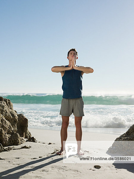 Junger Mann tun Yoga am Strand