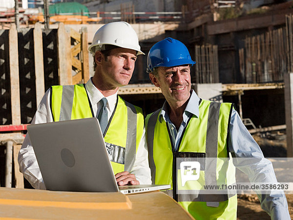 Reife Männer mit Laptop auf der Baustelle
