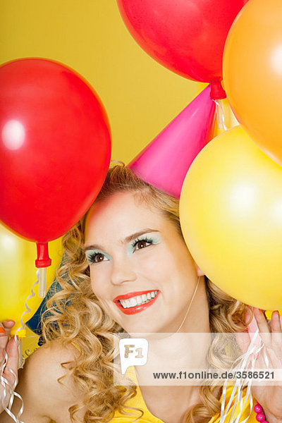 Young blonde woman with balloons against yellow background